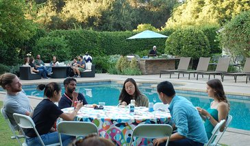 DataSAI Summer School Students sitting at a table next to a pool
