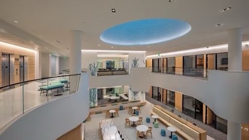 View of the interior of the Chen Neuroscience Research Building from the third floor gallery, it shows the tiled skylight, the third floor elevators, the second floor write up and social areas.