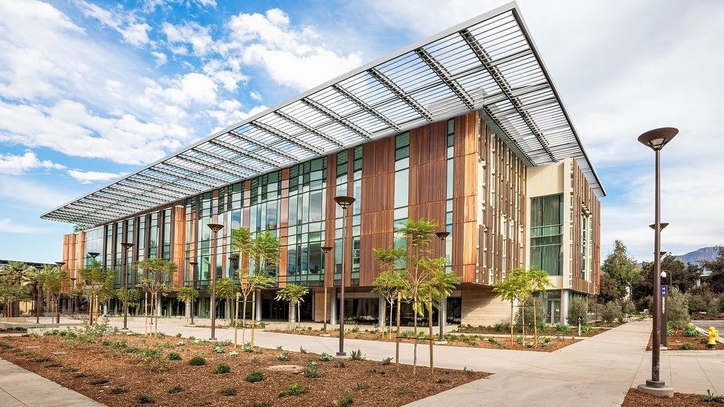 South side of the Chen Neuroscience Research building, it shows the large windows and copper facade of the exterior of the building, also Moore Walk, pathway and plant beds with young trees and succulents.