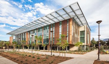 South side of the Chen Neuroscience Research building, it shows the large windows and copper facade of the exterior of the building, also Moore Walk, pathway and plant beds with young trees and succulents.