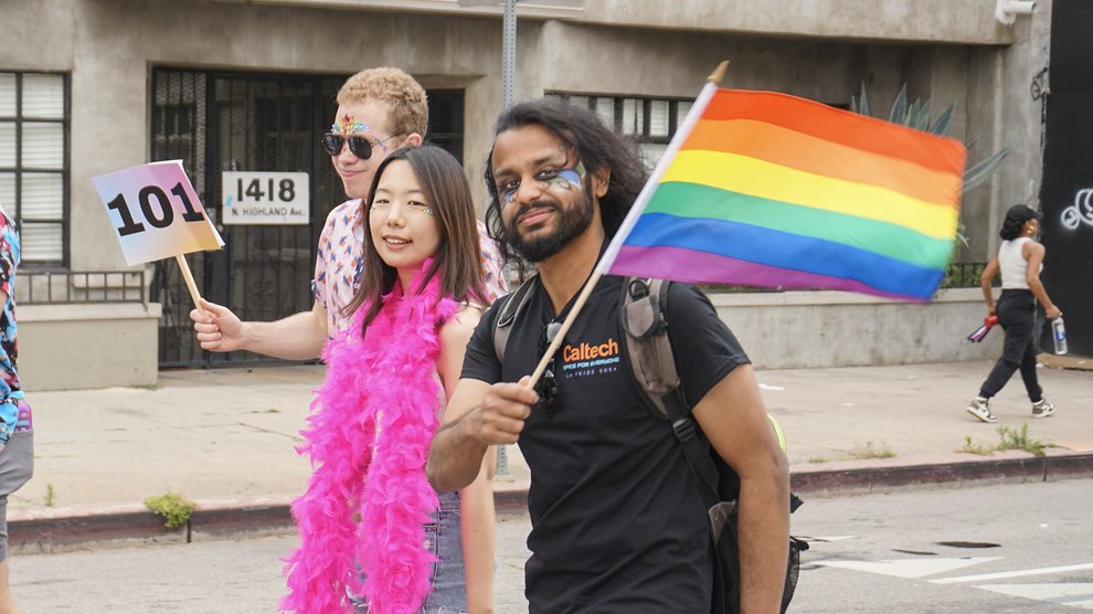 Soham Bhattacharya, postdoctoral scholar research associate in physics, waves a rainbow flag.
