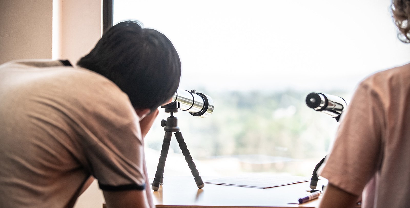 student looking into the sky through a telescope