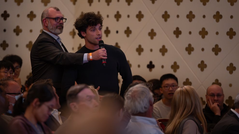 A student speaks into a microphone held by an event staff member