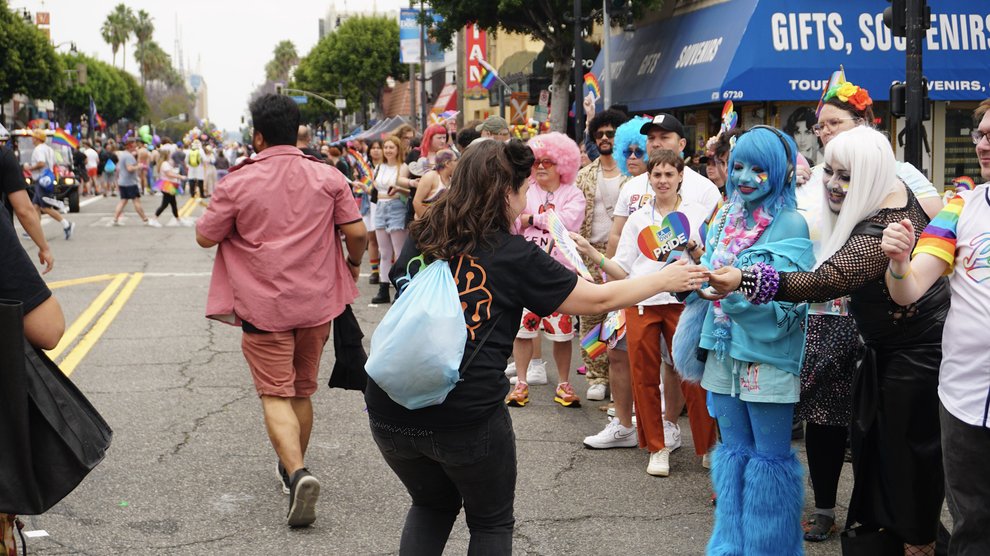 A person hands out Caltech pride-themed stickers to audience members.
