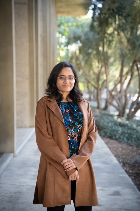 student in a brown coat standing outside on Caltech's campus