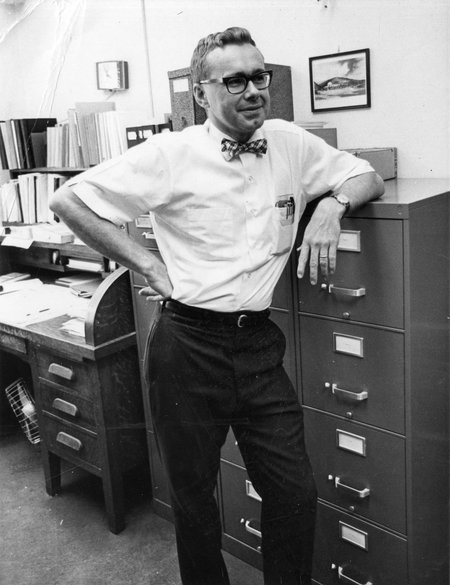 Professor Arden Albee, in 1967, stands by a file cabinet wearing a white short-sleeved shirt and a bowtie.