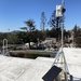 A QuantAQ sensor installed on a rooftop. Burned property from the fire is clearly visible in the background.
