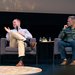 Cameron Hummels listens as Elias Most speaks during a panel on stage