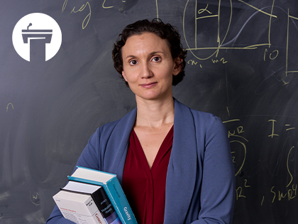 Image of Katerina Chatziioannou holding books in front of a chalk board