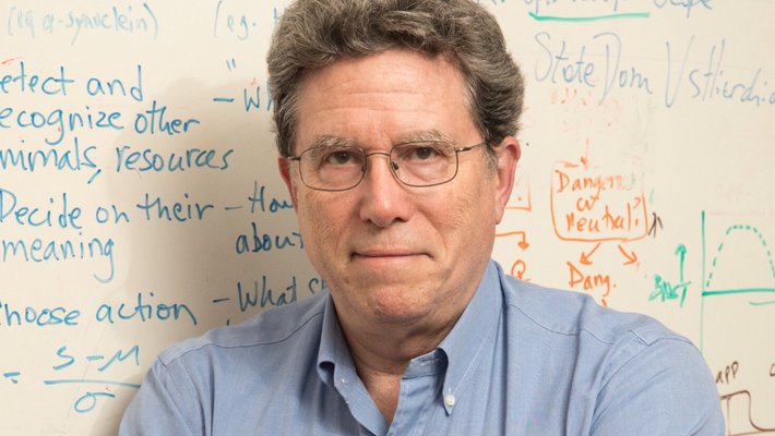 A man sitting in front of a whiteboard with graphs and notes on it