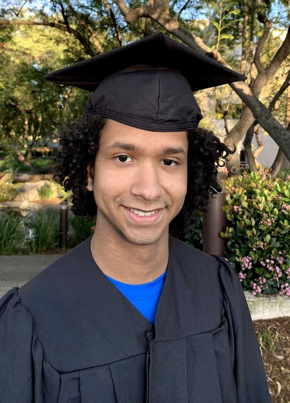 A portrait of Kenny Duran wearing a graduation robe and mortarboard.