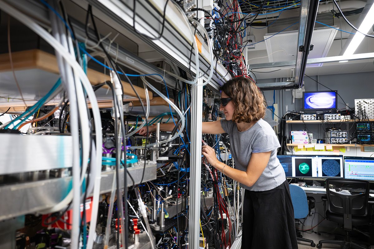 Hannah works in a lab filled with optical devices and chords.