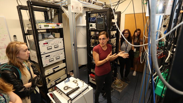 A scientist is seen talking to others in a lab full of equipment.