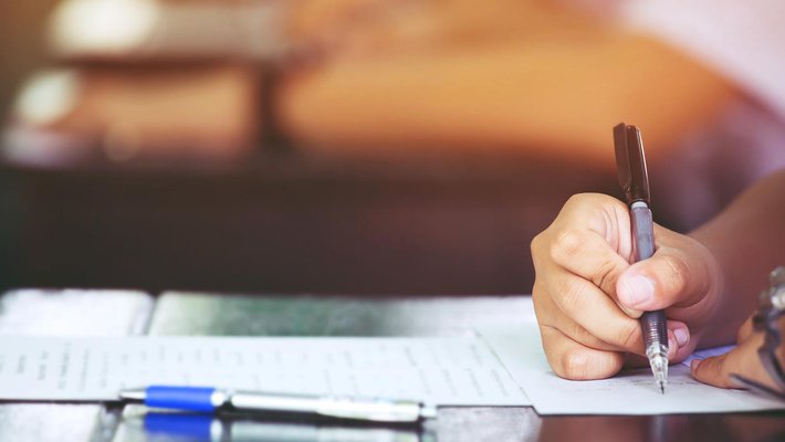 Stock photo of a person's hand writing on a paper at a desk