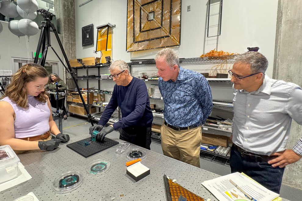Three researchers watch as Bill Gates makes an ultra-thin, flexible solar cell.