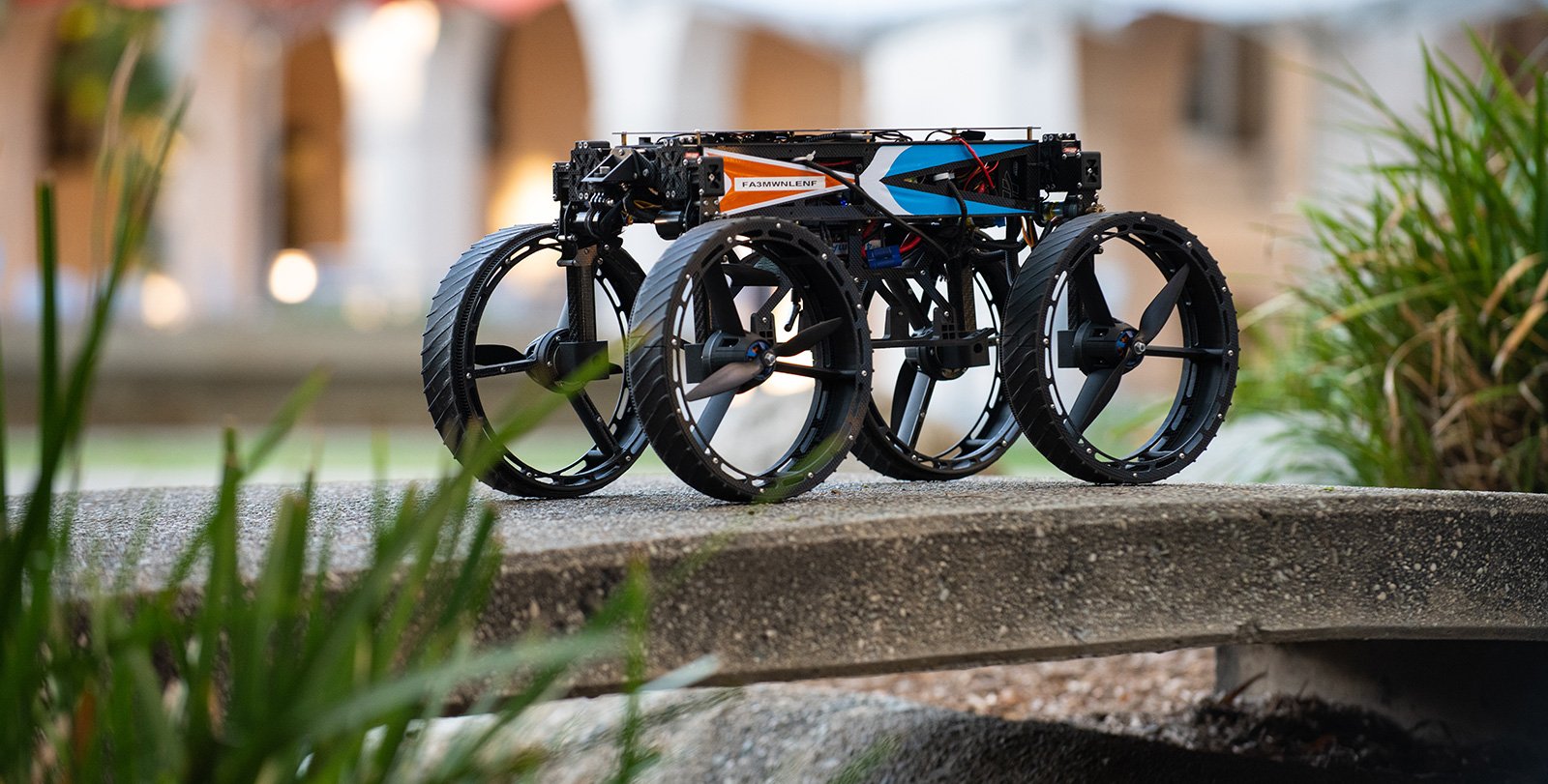 A small, four-wheeled robot perches on a cement bridge with plants on either side.