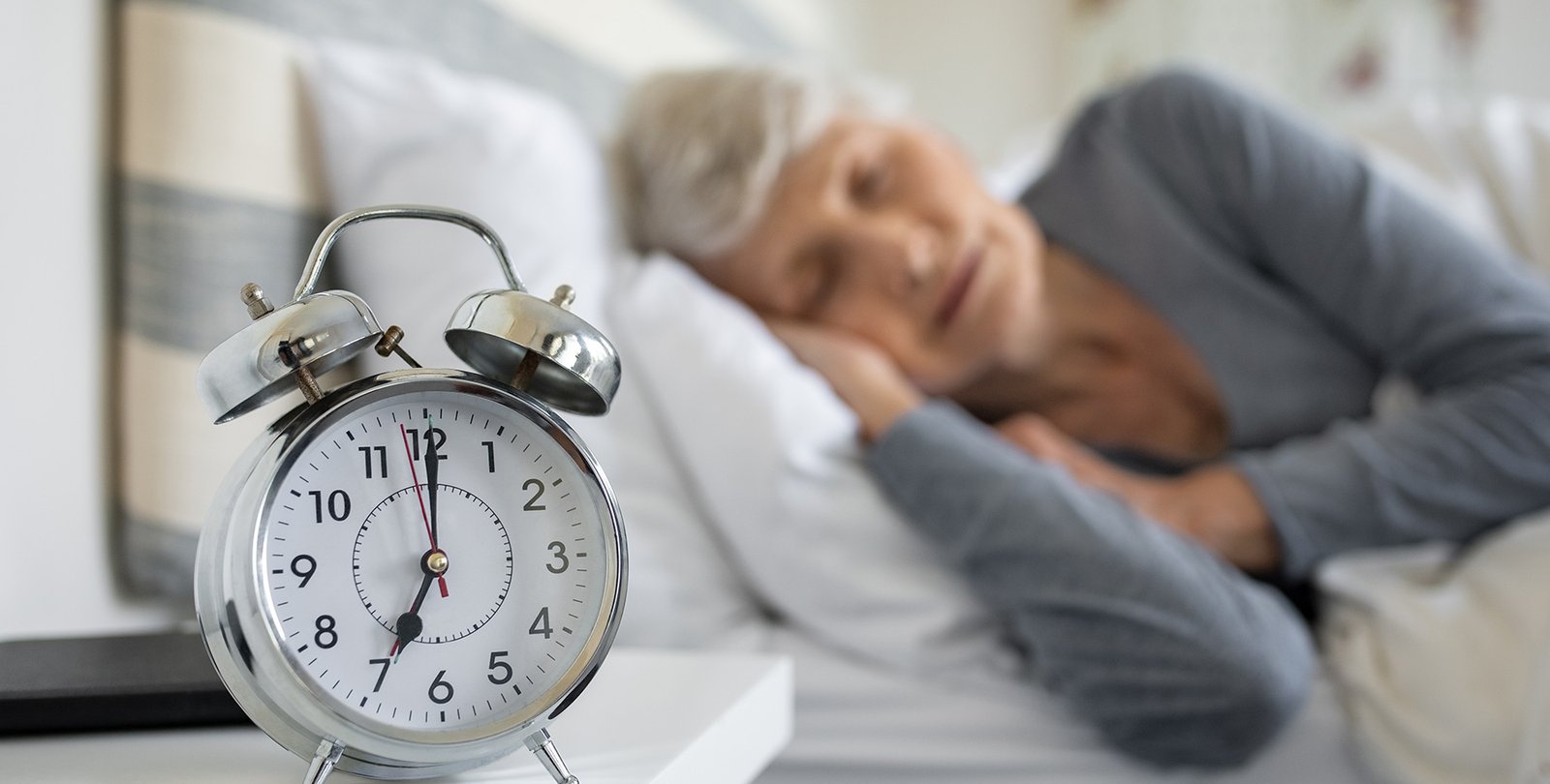 Stock image of a person sleeping next to an alarm clock