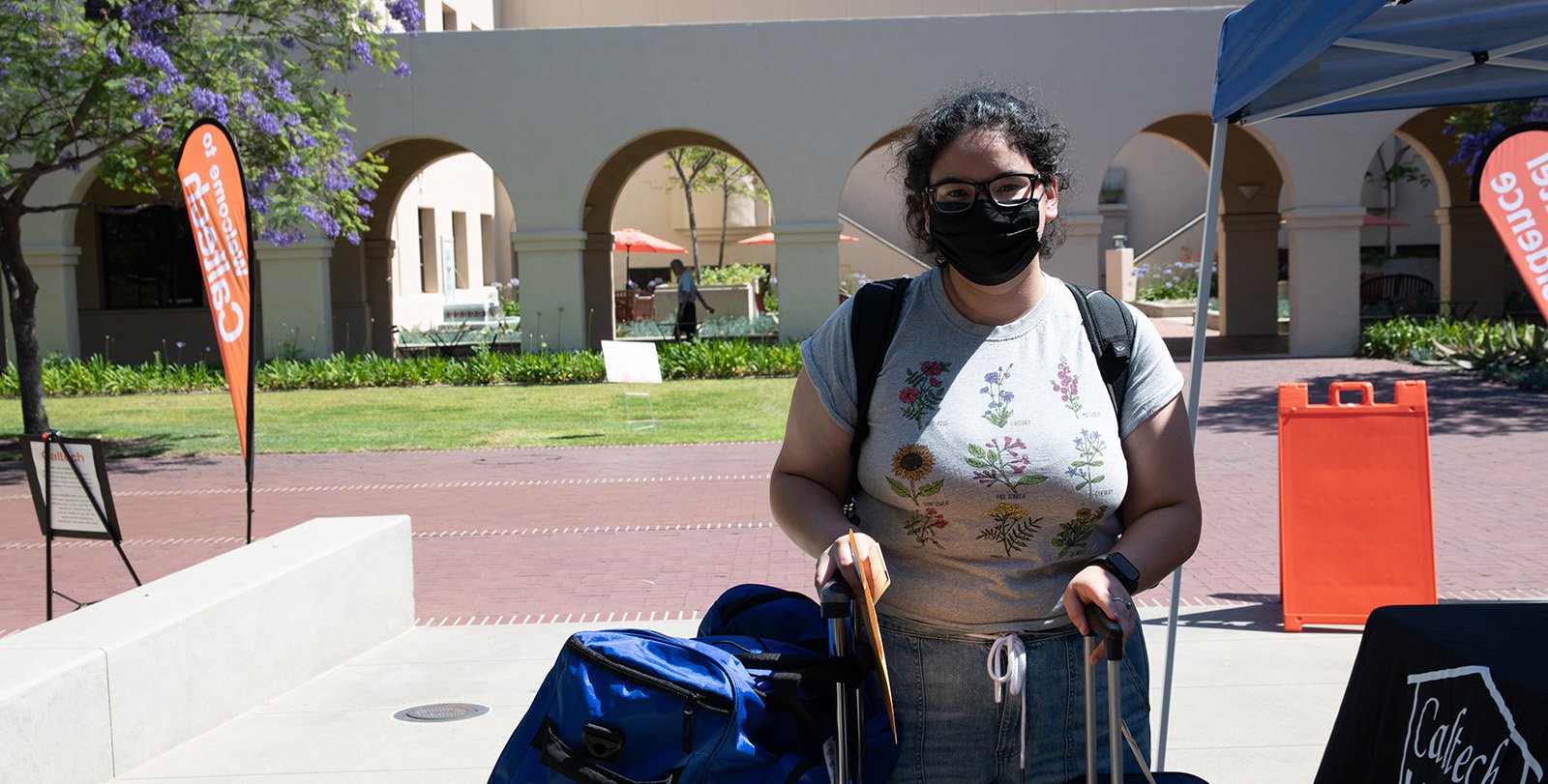 Student Jennifer Rodriguez stands with her luggage in front of the Moore Laboratory of Engineering