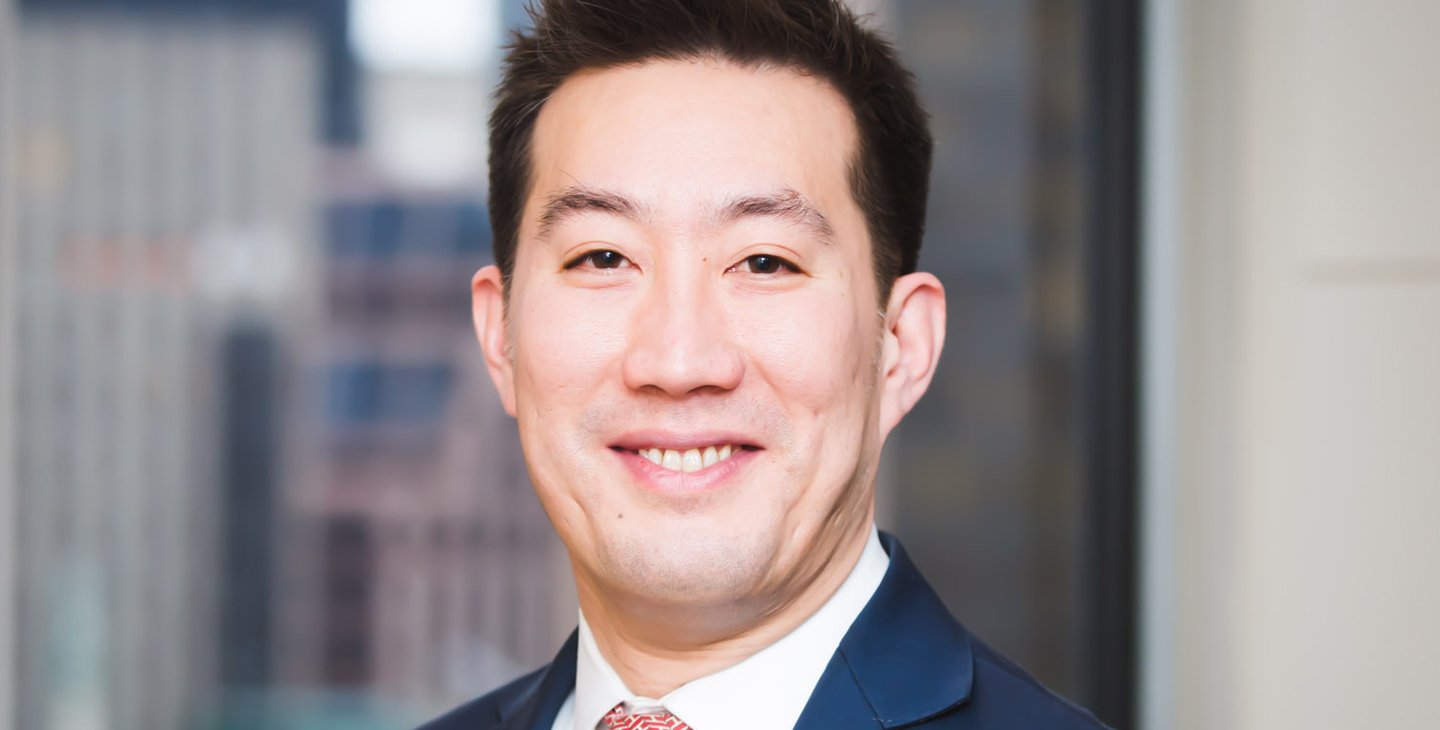 portrait photo of Ken Lee wearing a dark suit and red tie