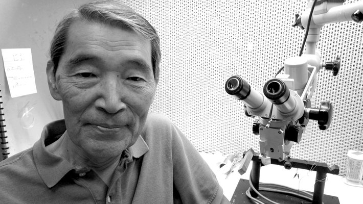 Masakazu (Mark) Konishi next to a microscope