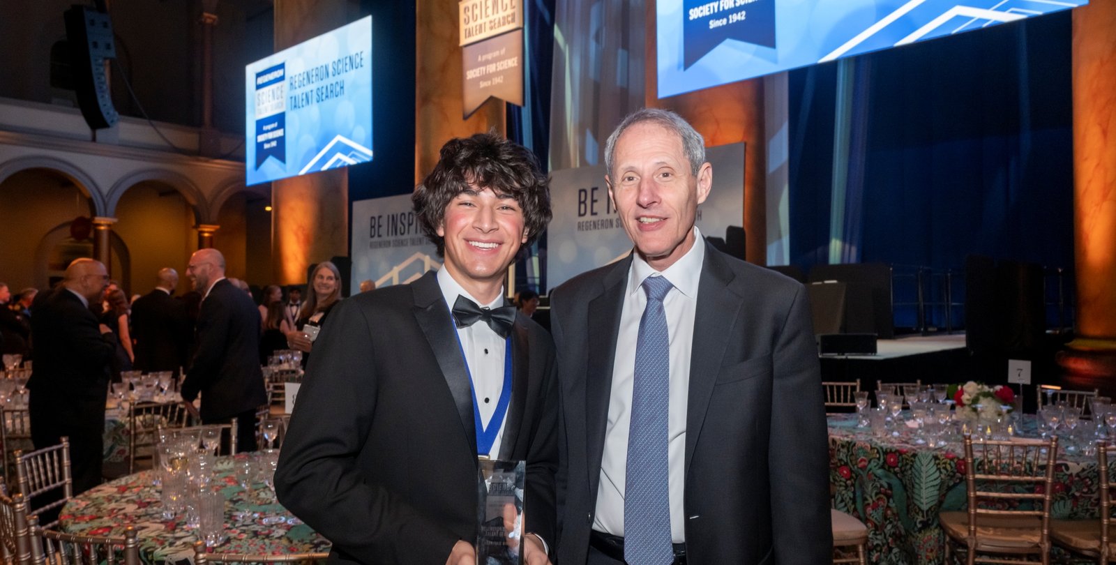 Regeneron Science Talent Search winner Matteo Paz and Caltech president Thomas Rosenbaum stand smiling at a formal event