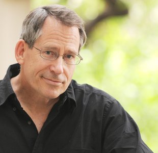 Professor John Preskill, a middle-aged white man, wears wire-rimmed glasses and a black shirt.