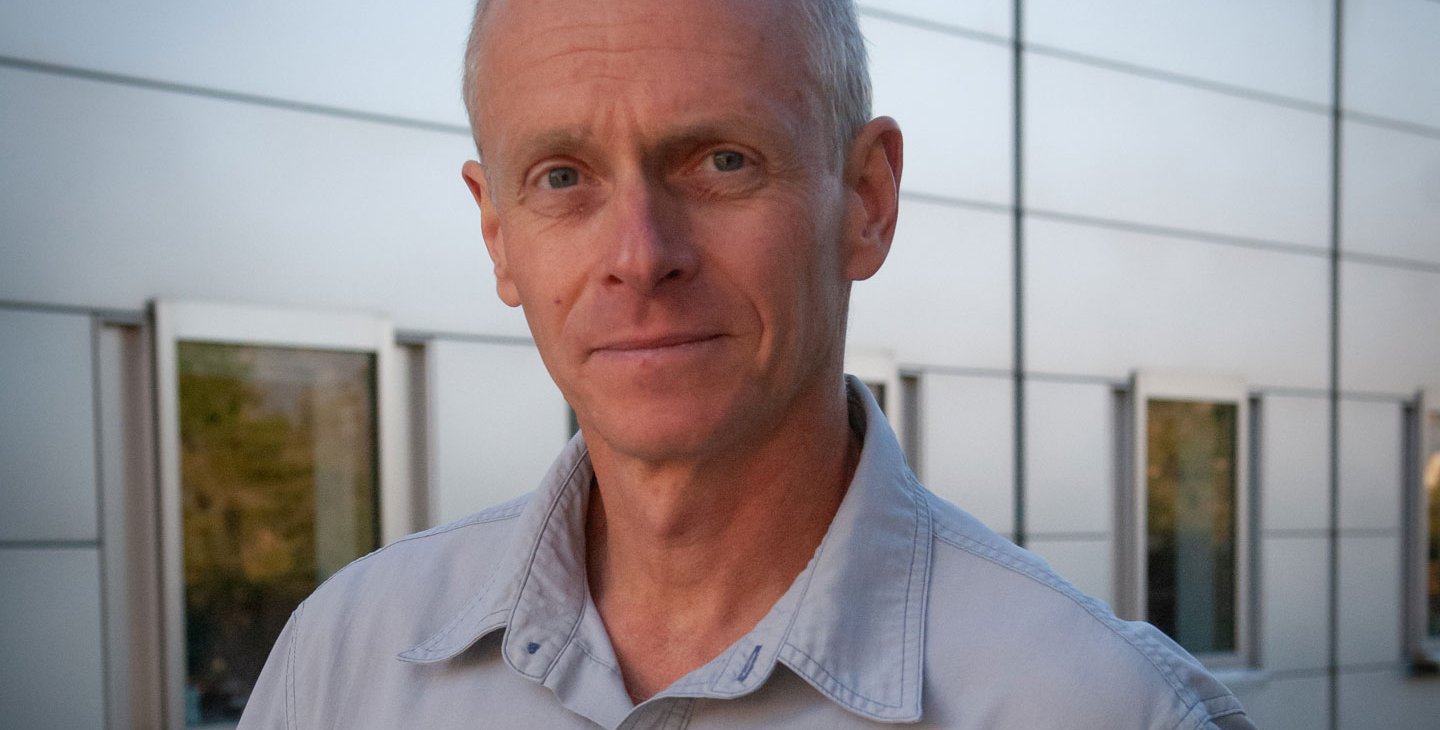 A portrait of Ralph Adolphs. He wears a light blue collard shirt.
