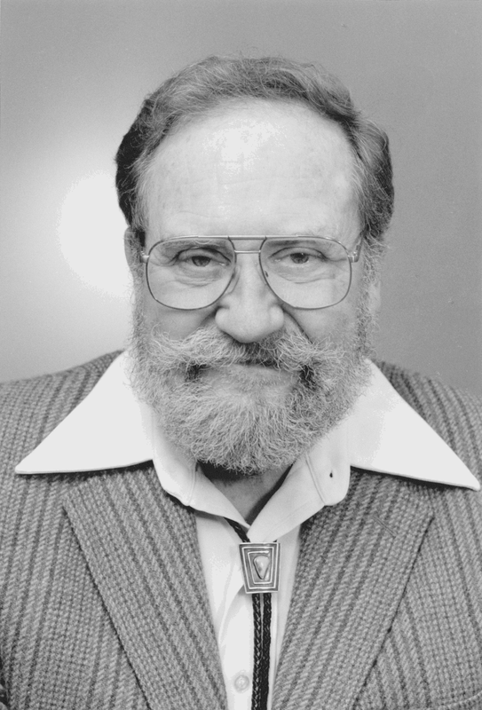 Black and white headshot of Ray Owen wearing a bolo tie