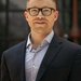 A portrait of Ryan Hadt. He wears a blazer and button-down shirt and glasses.