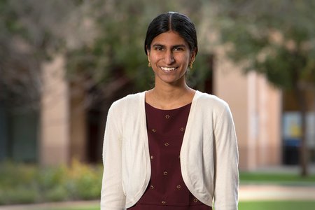 A portrait of Kavya Sreedhar. She wears a maroon blouse and white cardigan sweater
