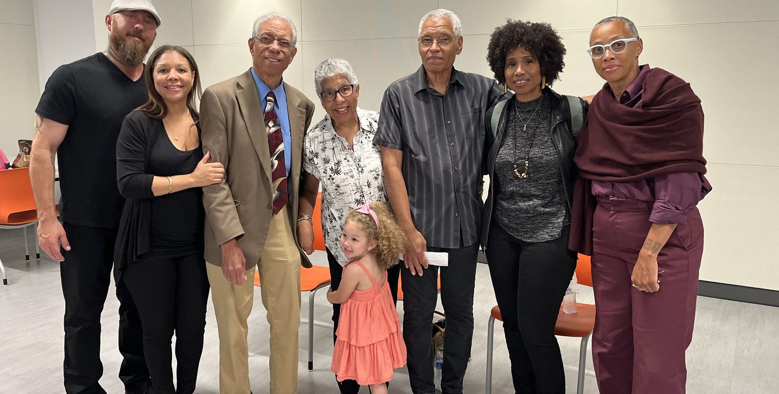 seven people and a child stand together smiling