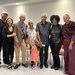 seven people and a child stand together smiling