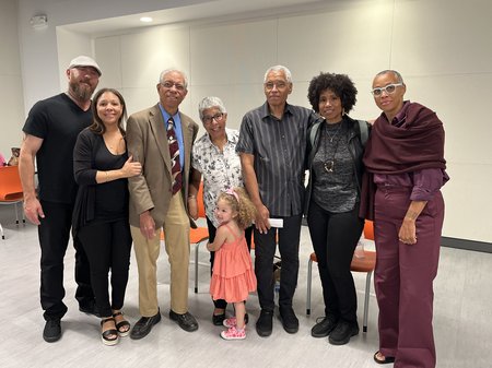seven people and a child stand together smiling