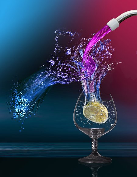 Water pouring into a glass with a lemon in it.