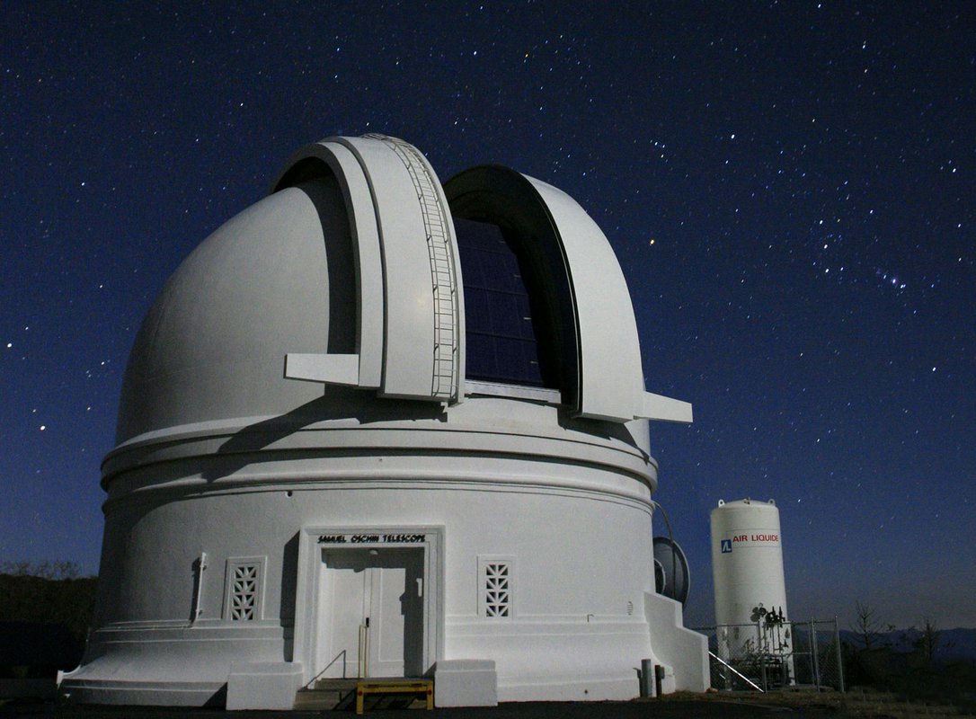 The 48-inch Samuel Oschin Telescope, a while dome with a blue sky in the background.