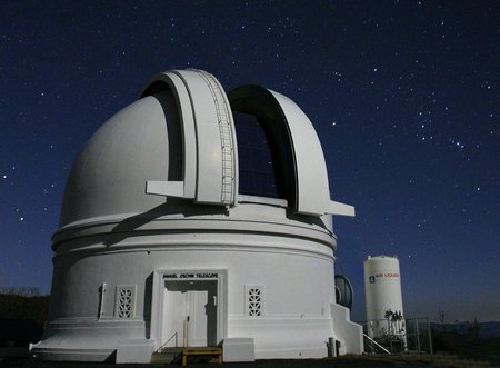 The 48-inch Samuel Oschin Telescope, a while dome with a blue sky in the background.