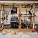 A tabletop system with a wooden frame, tubing, a glass cylinder, gauges, and pumps