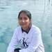 A portrait of Sreemanti Dey. She wears a sweater and sits in front of a body of water.