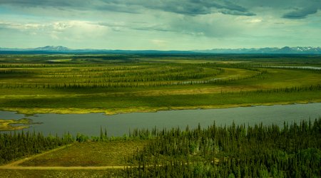 A horizontal river and green fields with a blue sky