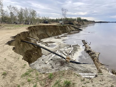 A dirt riverbank with receding edges along a river