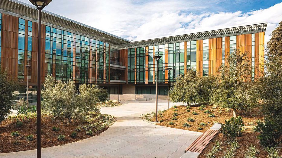 The Tianqiao and Chrissy Chen Institute for Neuroscience at Caltech, a modern building with glass windows, wood accents, and landscaped greenery, reflects innovation and nature.