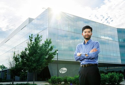 Man standing in front of a building with a Pfizer sign