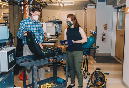 A man and a woman in face masks taking measurements using a machine