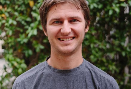 Picture of a smiling man standing in front of a hedge