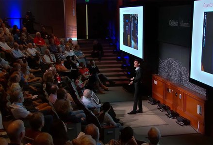 Man in front of a crowded auditorium giving a presentation