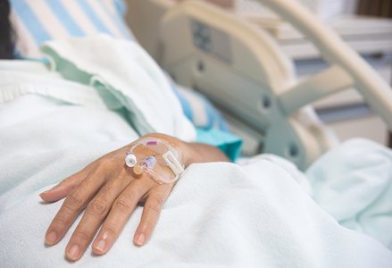 close-up of hand of person in hospital bed with IV inserted