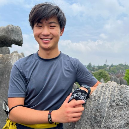 Undergraduate student Albert Huang in nature with mountains in the background.