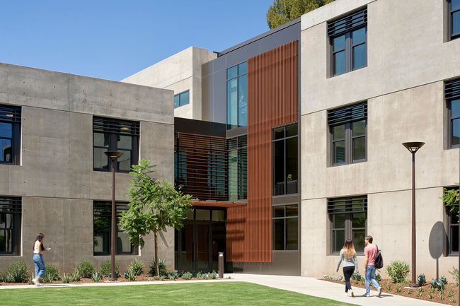 Students walking toward the entrance of Caltech's Bechtel residence on a sunny day.
