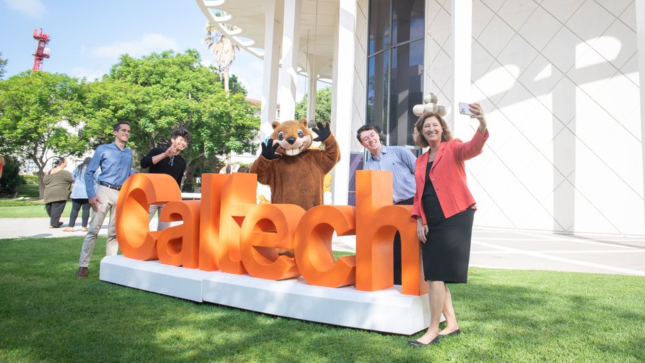 Laurie Leshin taking a selfie with Caltech's mascot and community members.