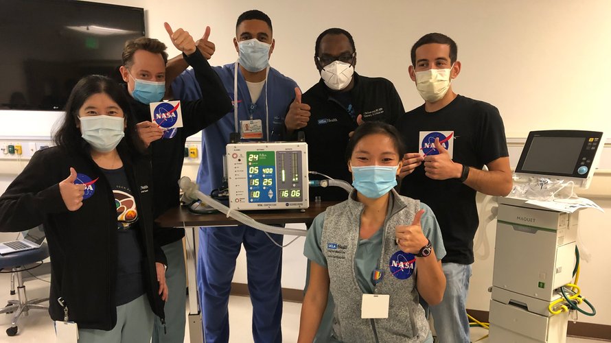 UCLA's Dr. Tisha Wang and colleagues posing in the lab with thumbs up, showing the NASA logo.